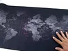 A hand is shown touching a large black mousepad with a world map printed on it. Náhled obrázku produktu