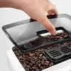 A hand is shown opening the lid of a coffee grinder, revealing coffee beans inside. Produktbild-Vorschau