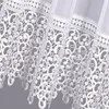 A close-up view of white lace curtains with intricate patterns. Produktbild-Vorschau