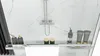 A close-up view of a shower shelf with toiletries and a shower head in the background. Produktbild-Vorschau