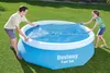 A man and a woman are placing a solar cover on a blue inflatable pool in a grassy yard. Produktbild-Vorschau