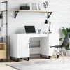 A modern white desk with a laptop and desk lamp, set against a white brick wall.