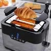 A toaster with a croissant on top, set on a table with oranges and toast in the background. Produktbild-Vorschau