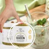 A hand reaching for a jar of pistachio cream next to a glass of pistachio dessert. Produktbild-Vorschau