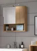 A bathroom cabinet with a mirror and open shelf, displaying various toiletries. Produktbild-Vorschau