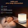 A child sleeping in bed next to a glowing night light on a bedside table. Voir les images du produit