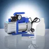 A vacuum pump with a gauge, a bottle of fluid, and a manual are displayed on a reflective surface against a gradient blue and white background. Náhľad obrázku produktu
