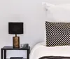 A bedside table with a lamp and a digital clock next to a bed with pillows. Anteprima dell’immagine prodotto