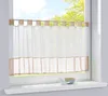A sheer curtain with a border hangs in a window. Produktbild-Vorschau