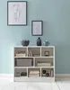 A white bookshelf filled with books and decorative items, set against a light blue wall. Produktbild-Vorschau