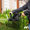 A person is using an electric hedge trimmer to trim a bush. Náhľad obrázku produktu