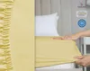 A close-up of a yellow fitted sheet being placed on a mattress, with certifications visible in the background. Produktbild-Vorschau