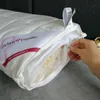 A hand is shown opening a zipper on a white pillow, revealing the filling inside. Produktbild-Vorschau