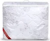 A white quilted duvet in its clear plastic packaging with a floral pattern and a red label. Náhled obrázku produktu