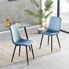 Two light blue velvet dining chairs with diamond quilting and black metal legs are placed on a rug in front of a glass-topped dining table. Anteprima dell’immagine prodotto
