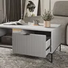 A modern living room scene featuring a gray coffee table with an open drawer, a magazine, a mug, and a plant. Náhled obrázku produktu