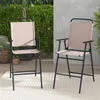 Two beige folding bar stools with black frames are shown outdoors on a patio. Produktbild-Vorschau