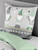 A pillow with a gnome pattern is placed on a bed next to a green pillowcase. Produktbild-Vorschau