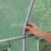 A hand is shown connecting two metal poles of a greenhouse frame, which is covered by a green transparent PE plastic sheet. Produktbild-Vorschau