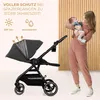 A woman holding a baby stands next to a stroller, with promotional text and icons in the upper left corner. Produktbild-Vorschau