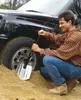 A man is using a shovel to dig out a car tire stuck in sand. Náhled obrázku produktu