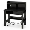 A black desk with a hutch, a drawer, and an open shelf, shown from the front with a power cord plugged in. Produktbild-Vorschau