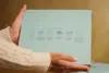 Hands holding a light blue box with diagrams and text on it. Anteprima dell’immagine prodotto