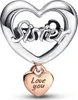 A silver heart-shaped charm with the word "Sister" cut out, and a small rose gold heart charm hanging from it with the words "Love you" engraved. Podgląd zdjęcia produktu
