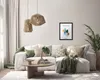 A modern living room scene with a white sofa, coffee table, and decorative items, featuring a framed picture on the wall. Produktbild-Vorschau
