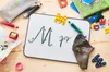 A whiteboard with letters and writing, surrounded by school supplies on a wooden surface. Voir les images du produit