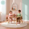 Two young children are playing with building blocks at a wooden table and chairs in a brightly lit room. Produktbild-Vorschau
