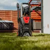 A pressure washer is placed on a lawn in a backyard setting. Voir les images du produit