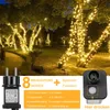 A park or garden setting with trees decorated with warm white string lights at night. Produktbild-Vorschau