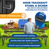 A man is sitting at a picnic table with food and drinks, set up outdoors on grass. Produktbild-Vorschau