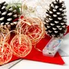 A close-up of a Christmas decoration featuring wire balls with LED lights, pine cones, and a battery pack. Náhľad obrázku produktu