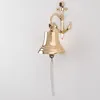 A brass ship's bell with an anchor mount is shown on a white wall. Produktbild-Vorschau