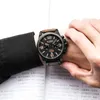 A person's wrist wearing a watch, with an open book in the background. Náhled obrázku produktu