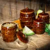 Several brown ceramic fermentation pots are arranged on a burlap cloth and a wooden table, with some cabbage in the background. Podgląd zdjęcia produktu