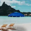 A beach scene with two lounge chairs, a blue umbrella, and overwater bungalows in the background. Voir les images du produit