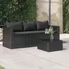 A black rattan sofa with dark gray cushions and a matching coffee table are placed on a paved patio, with a lush green wall of plants in the background. Náhľad obrázku produktu