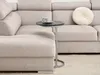 A small round side table with a marble top and metal base is placed next to a large, light-colored sectional sofa. A white coffee cup and saucer sit on the table. A round, tufted cushion is on the sofa. Náhled obrázku produktu
