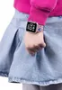 A child's arm wearing a digital watch with a pink band featuring a blue Stitch print. The child is wearing a pink long-sleeved shirt and a denim skirt. Produktbild-Vorschau