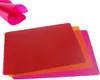 Three flexible cutting mats are stacked on a white background. A pink sheet is partially visible in the upper left corner, folded and curved. Voir les images du produit