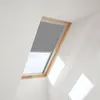 A skylight window with a gray roller blind partially lowered, set against a white wall. Produktbild-Vorschau