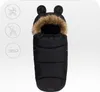 A black baby footmuff with a fur-lined hood and bear ears, displayed on a white background with icons for a stroller and a sled. Náhled obrázku produktu