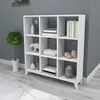 A white cube shelf unit filled with decorative items and books, placed against a gray wall and on a light gray floor with a rug. Produktbild-Vorschau