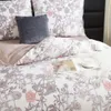 A close-up view of a bed with floral patterned bedding, a decorative pillow, and a cup of tea on a tray. Podgląd zdjęcia produktu