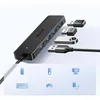 A black Ugreen USB hub with four USB ports is shown with several USB devices plugged in. Below the hub, icons represent devices that can be connected, such as a mouse, keyboard, flash drive, webcam, and printer. Produktbild-Vorschau