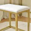 Close-up of a white upholstered stool with a gold metal frame. Produktbild-Vorschau