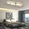 A modern bedroom with a bed, nightstands, and artwork, featuring a contemporary ceiling light. Produktbild-Vorschau